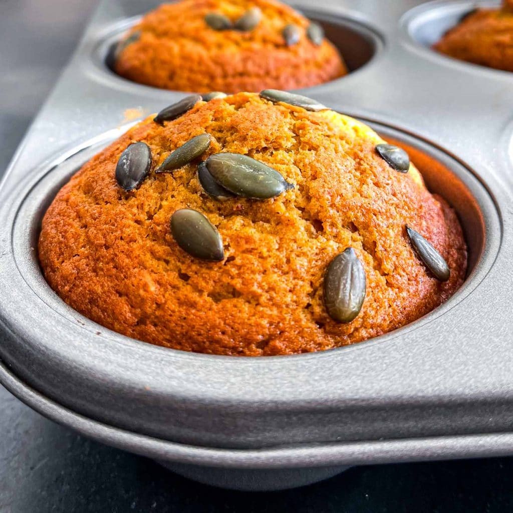 A close-up of pumpkin muffins in a grey muffin tin.