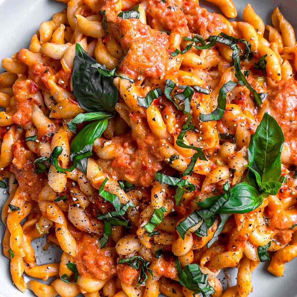 A closeup of creamy tomato pasta, topped with fresh basil.