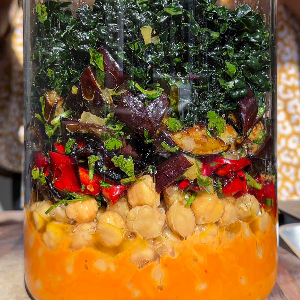 A layered chickpea salad in a glass jar.