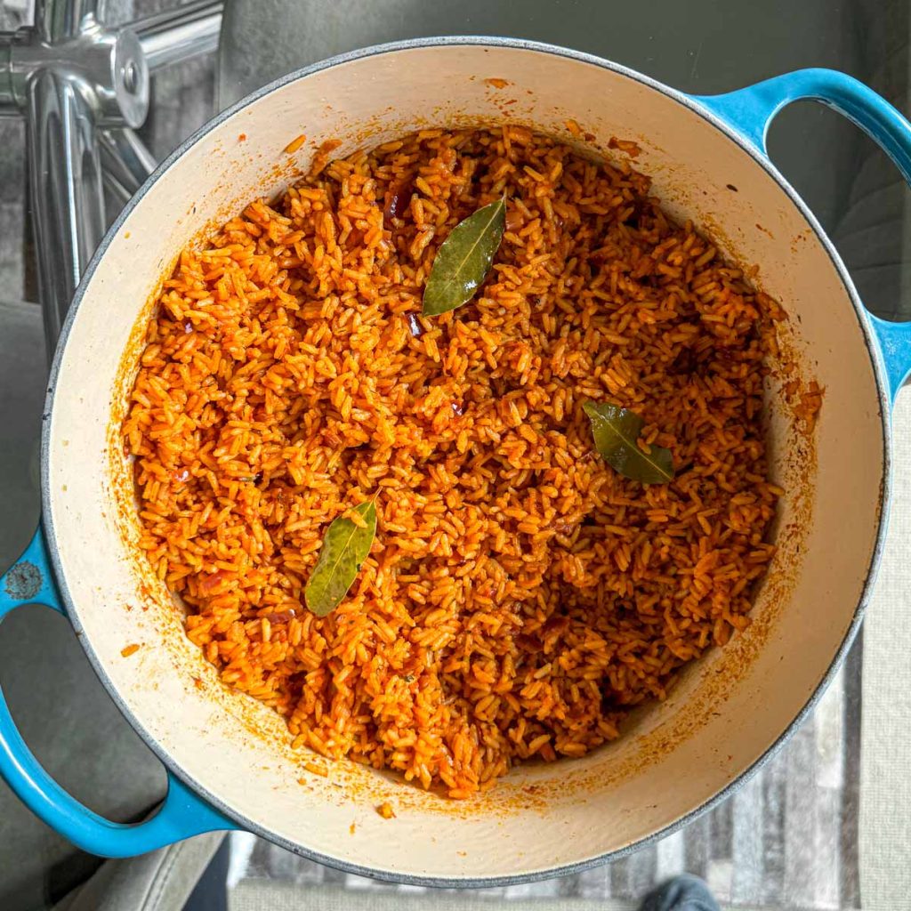 Oven baked jollof rice, made with long grain rice, served in a blue cast iron pot.