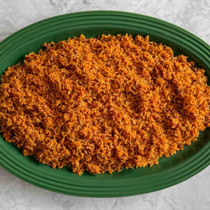 Oven baked Jollof Rice, served on a green platter.