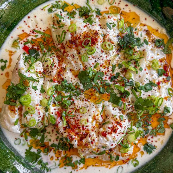 A closeup shot of the coconut milk poached fish recipe, served in a dark green platter.