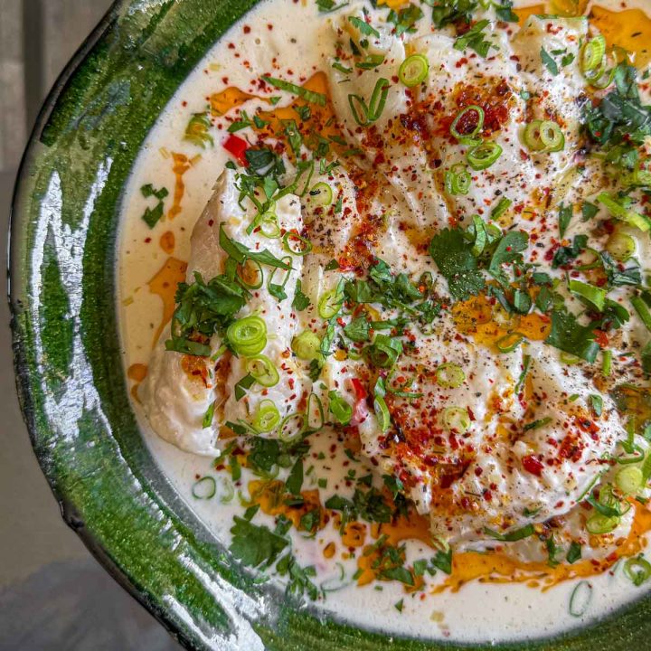 A closeup shot of the coconut milk poached fish recipe, served in a dark green platter.