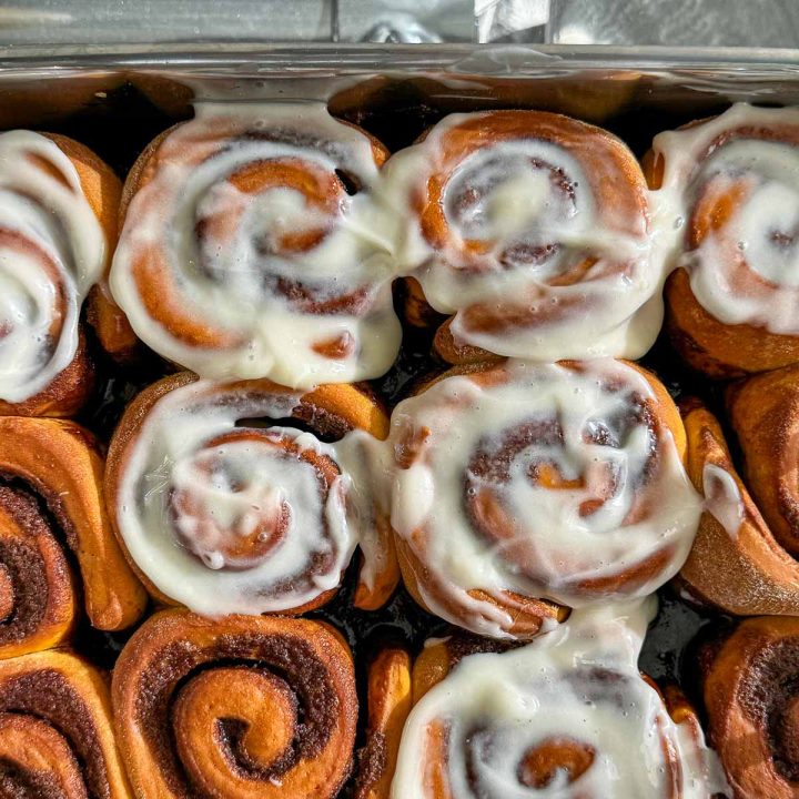 A tray of half frosted pumpkin cinnamon rolls.