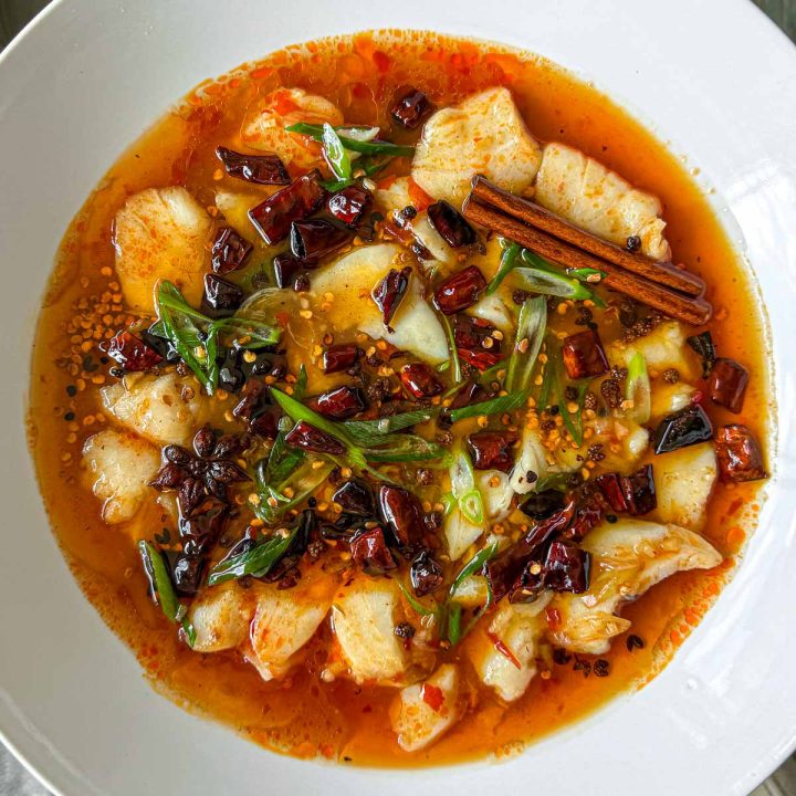 Spicy Sichuan fish, served in a white shallow bowl.