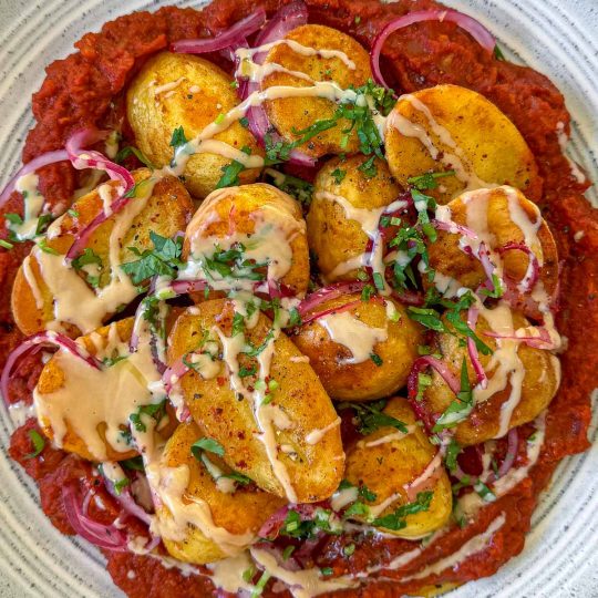 Crispy roast potatoes, served over a rich masala sauce and topped with yoghurt and coriander.