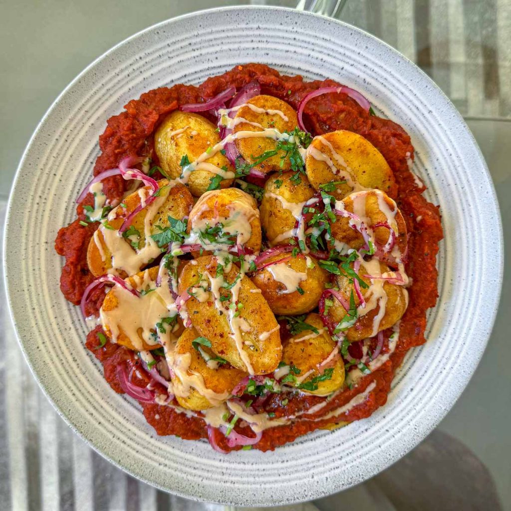 Crispy roast potatoes, served over a rich masala sauce and topped with yoghurt and coriander.