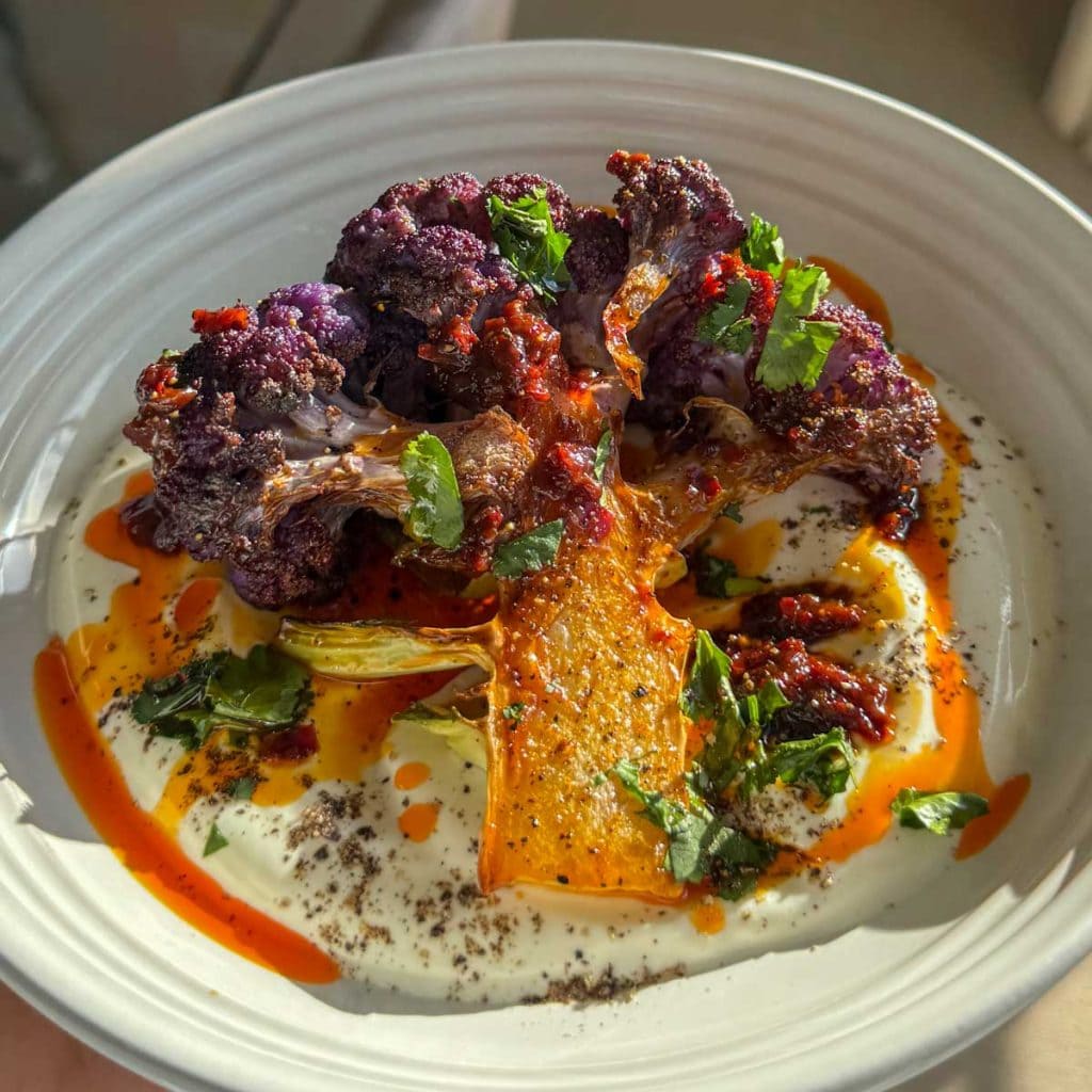 Roasted purple cauliflower, served over thick Greek yoghurt and topped with harissa honey butter.