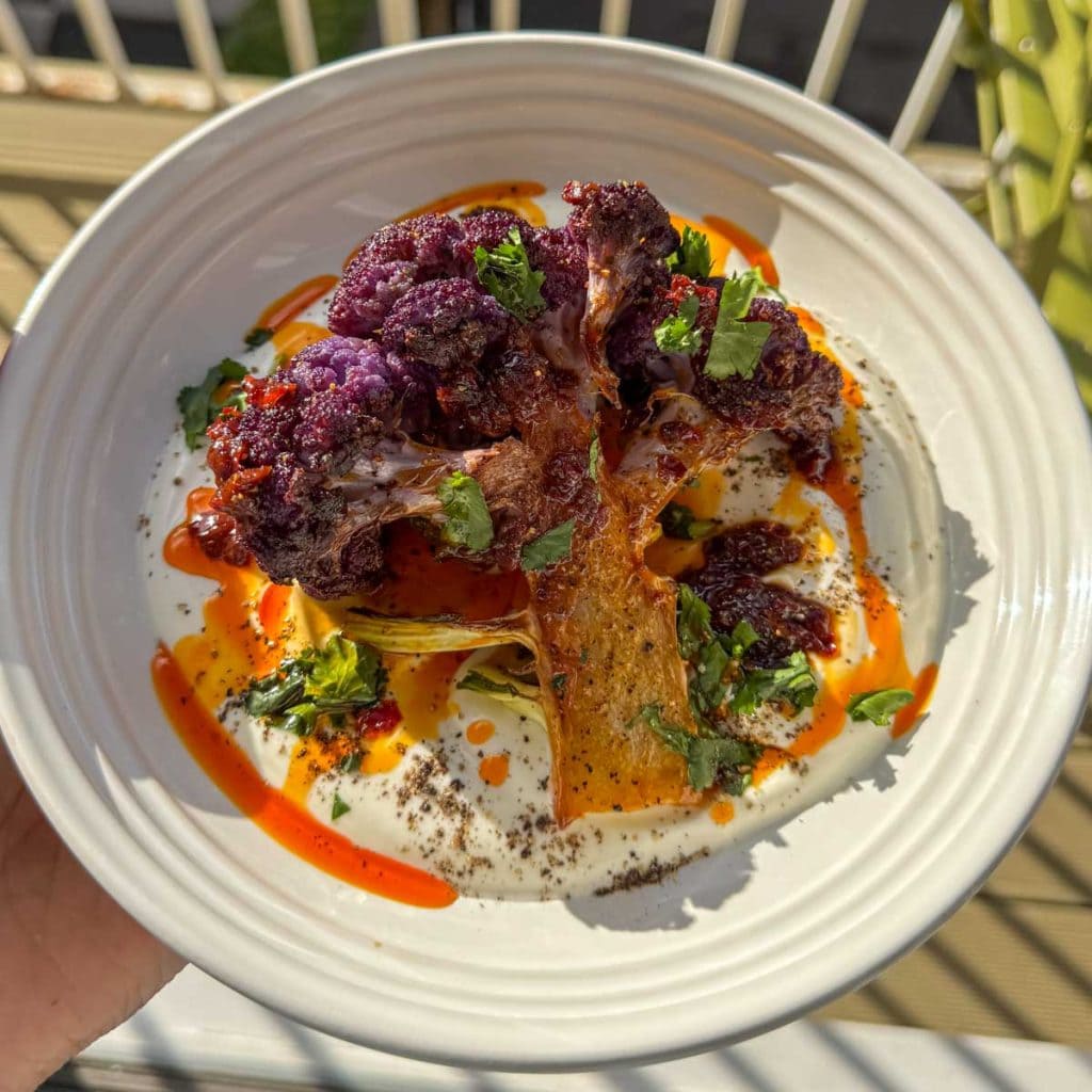 Roasted purple cauliflower, served over thick Greek yoghurt and topped with harissa honey butter.