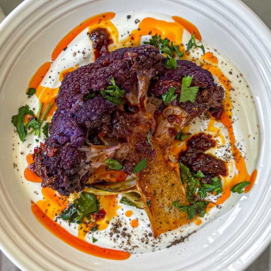 Roasted purple cauliflower, served over thick Greek yoghurt and topped with harissa honey butter.