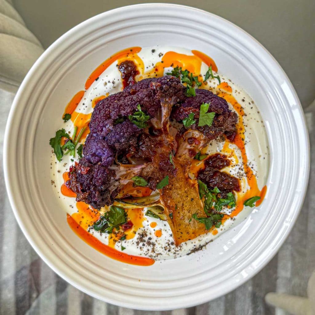 Roasted purple cauliflower, served over thick Greek yoghurt and topped with harissa honey butter.