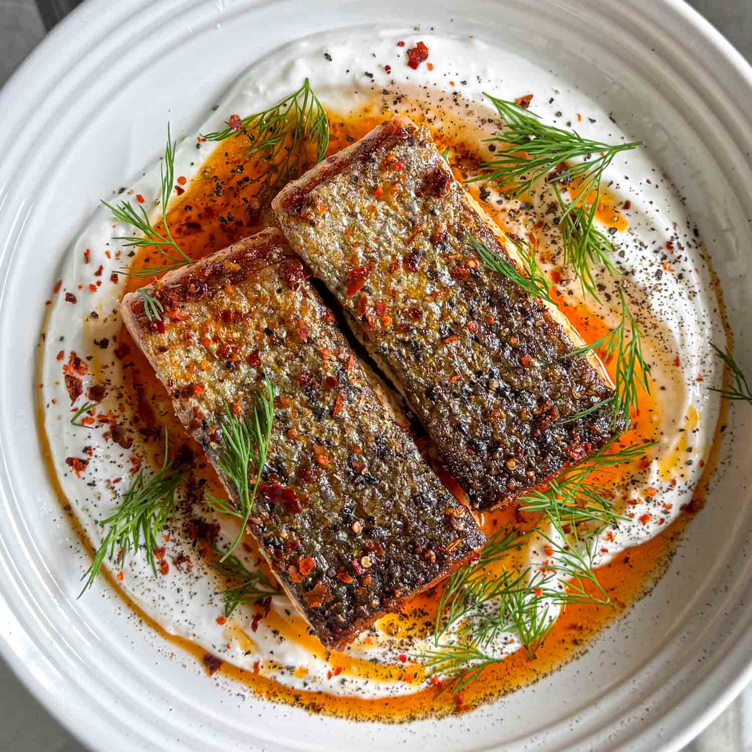 Crispy skin salmon, served over garlic yoghurt and topped with spiced butter