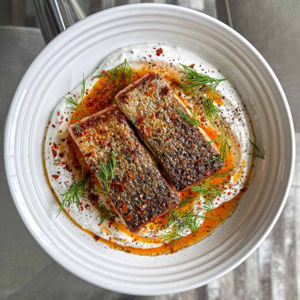 Crispy skin salmon, served over garlic yoghurt and topped with spiced butter
