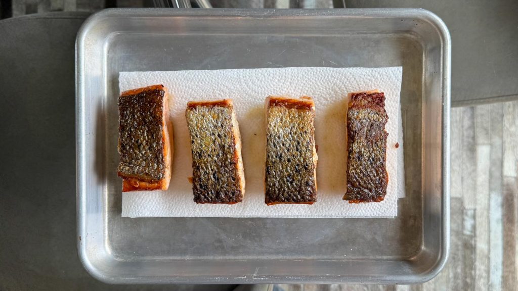 Crispy salmon skin, draining on kitchen towel.