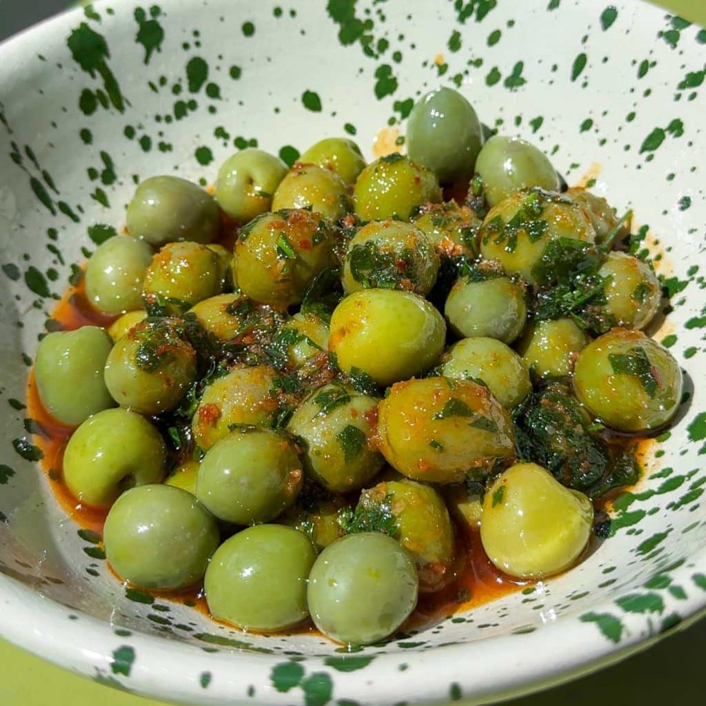 Close-up of olives coated in nduja marinade.