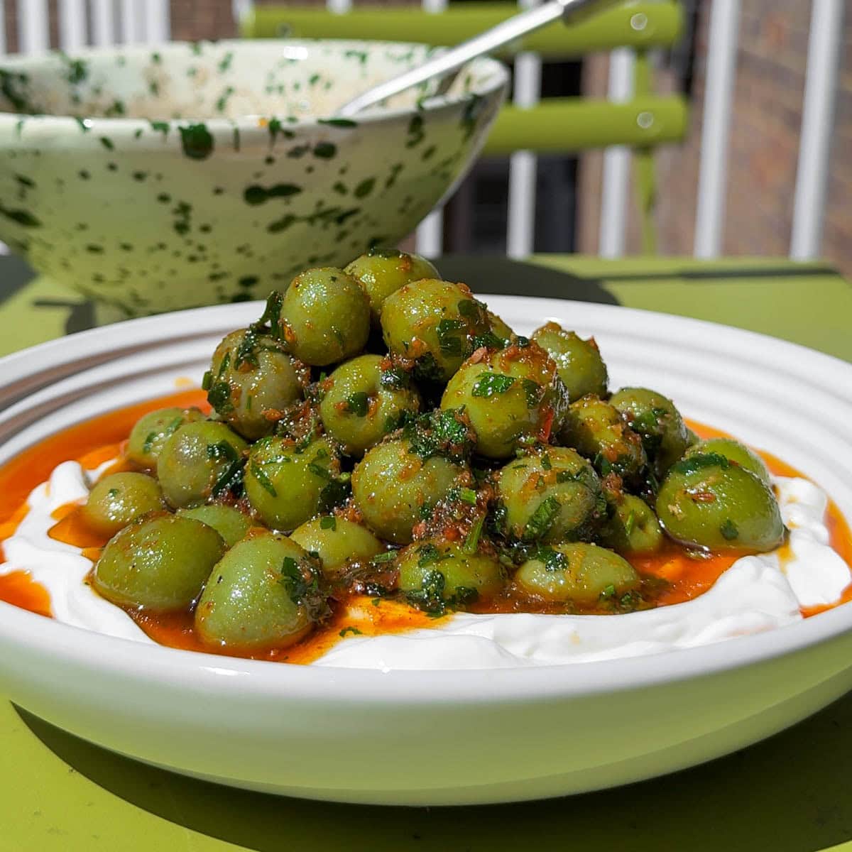 Bowl of Nduja Marinated Olives with parsley garnish.