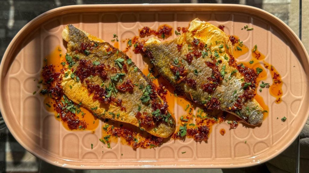 Crispy fish and sauce captured in the sun, the colours glowing in natural light.