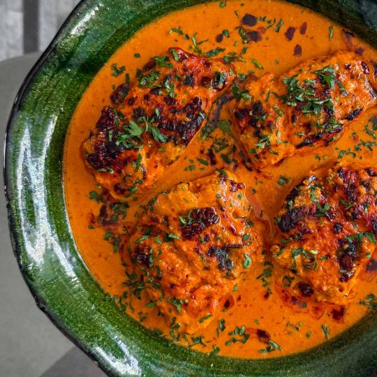 Close-up of cod loins in a rich sambal and coconut sauce with blistered, caramelised edges.