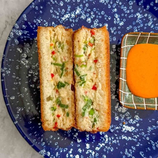Close-up of the cross section of the fish and prawn toast showing the thick, juicy filling between two slices of golden bread.