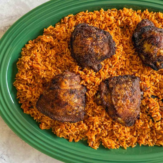 An overhead shot of grilled chicken, served over jollof rice.