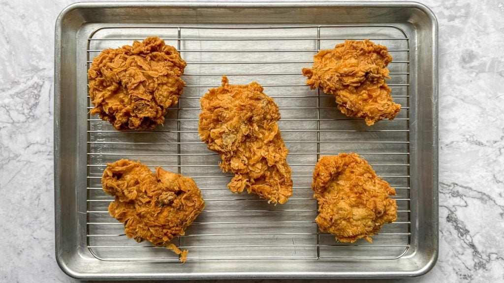 Overhead shot of Lemongrass Fried Chicken resting on a wire rack, light catching the crunchy surface.