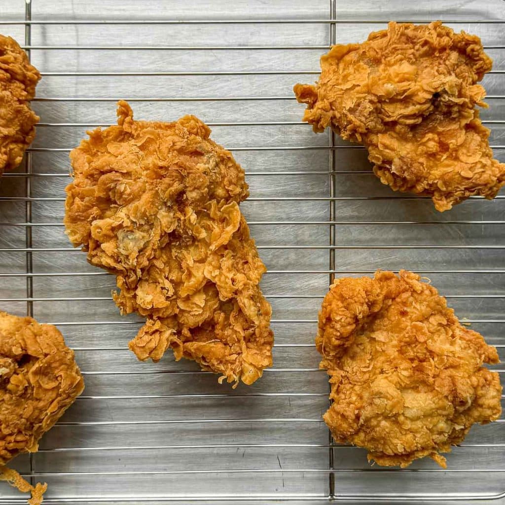 Freshly fried Lemongrass Fried Chicken pieces cooling on a wire rack, beautifully textured and golden.
