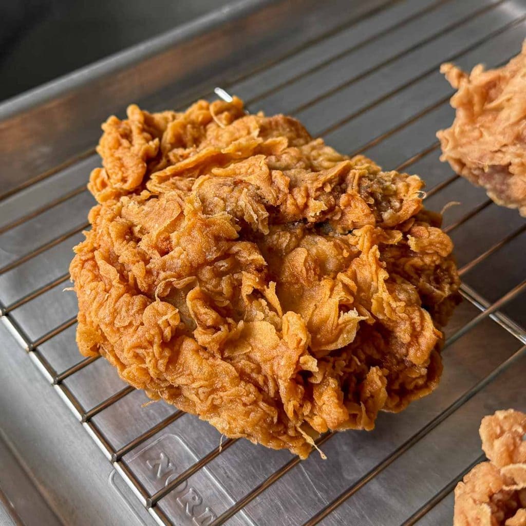 Close-up of Lemongrass Fried Chicken on cooling rack with craggy, golden crust.