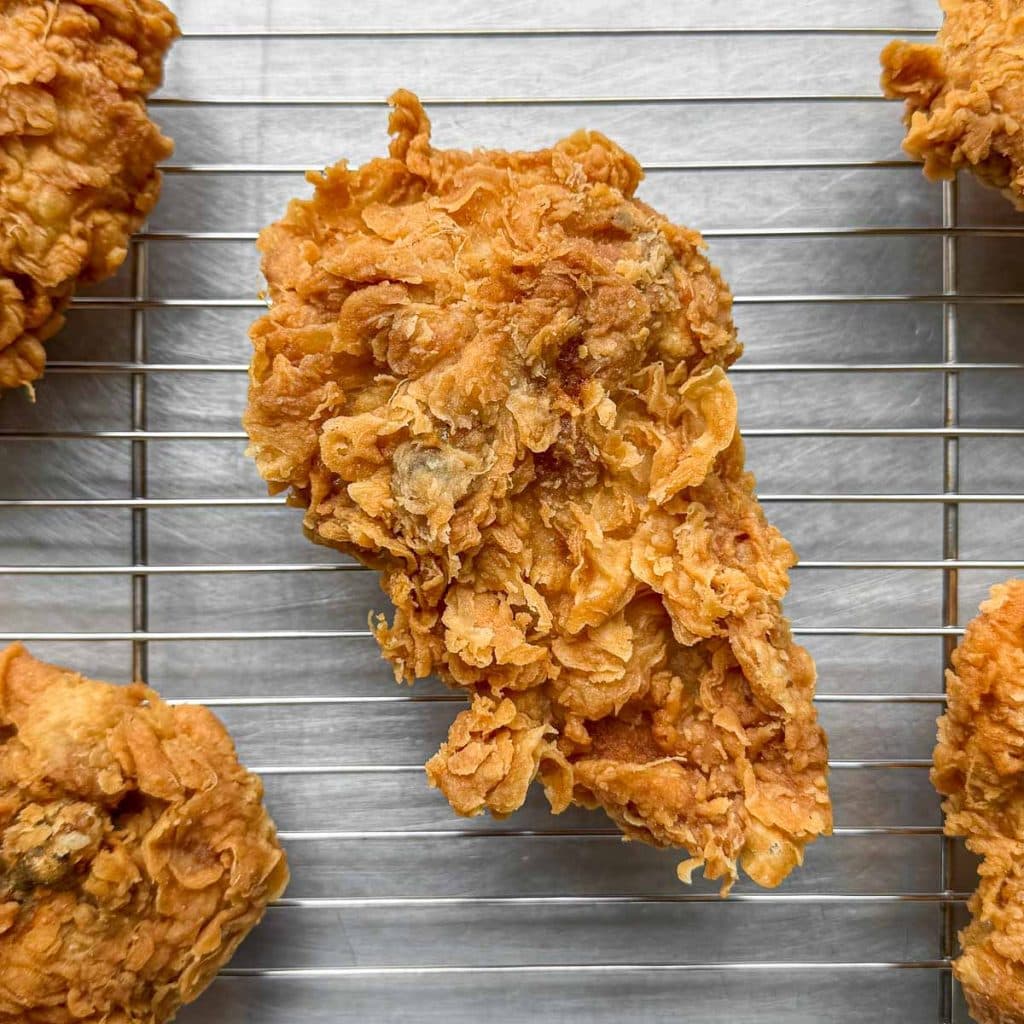 Lemongrass Fried Chicken resting on a wire rack, showing its crisp, golden coating up close.