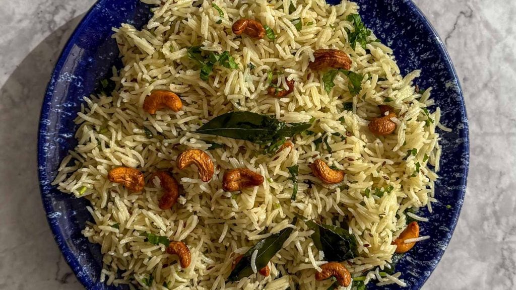 A closeup of Spiced Curry Leaf Rice, topped with fried curry leaves and toasted cashew nuts.