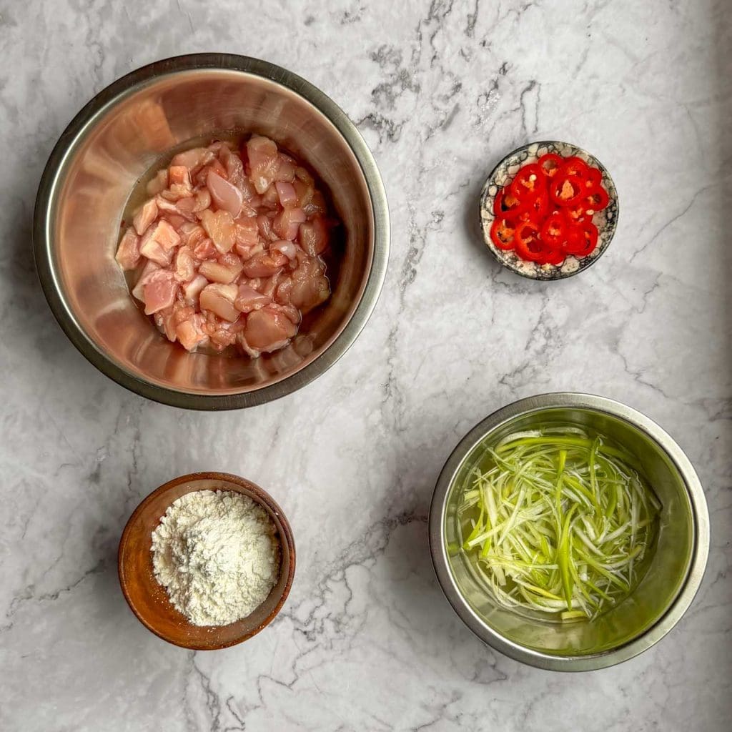 A selection of ingredients, including chicken thighs, spring onions, cornflour and chilli.