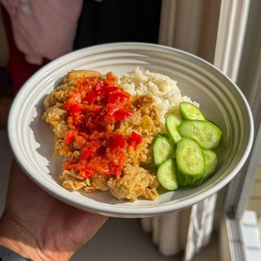 Indonesian smashed fried chicken, topped with sambal and served with rice and cucumber.