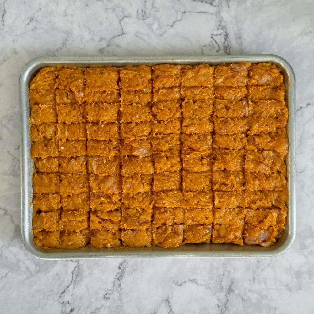 Sheet pan chicken kebabs, spread evenly in a baking tray ready for the oven.