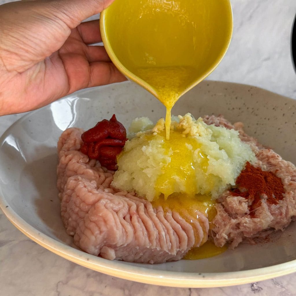 Adding butter to the chicken kebab mix.