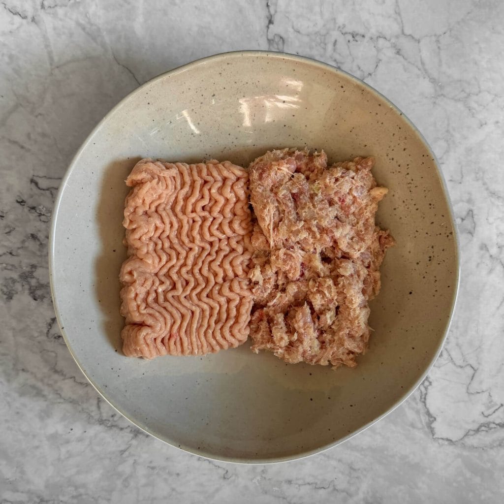 Chicken breast mince and blitz up chicken thigh meat in a white bowl.