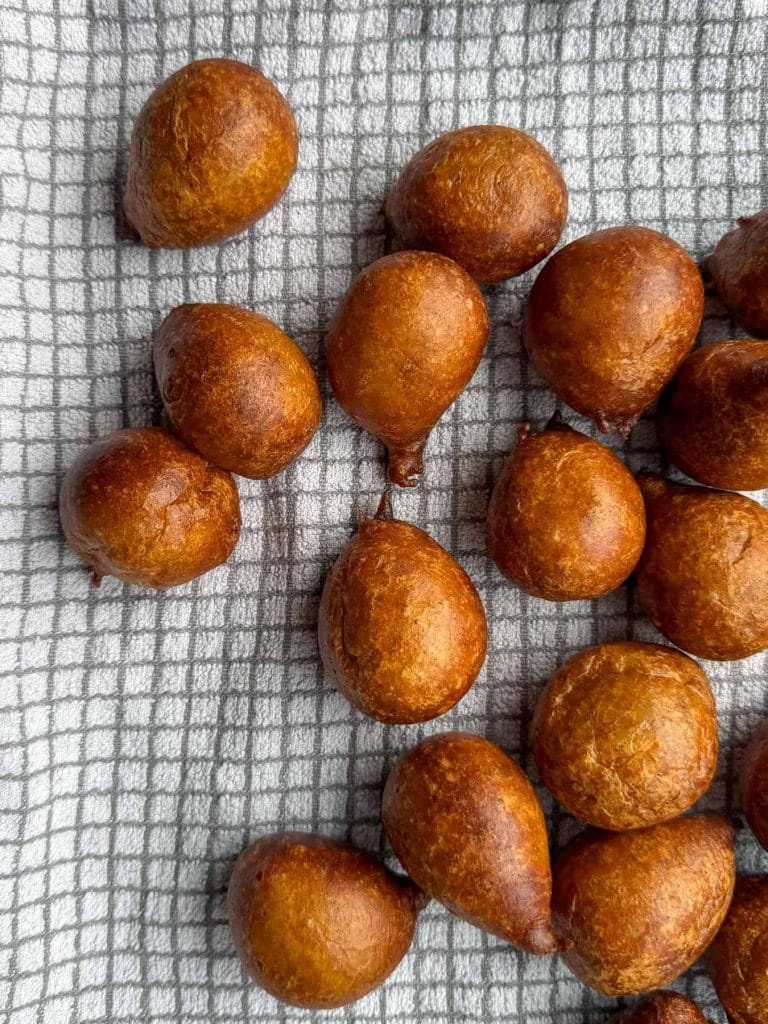 Freshly fried plantain puff puff draining on a tea towel