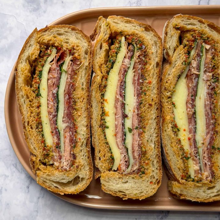 Muffuletta sandwich filled with homemade olive salad, Italian cured meats and cheese.