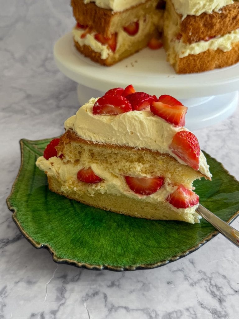A slice of strawberry cloud cake with mascarpone cream, served on a green plate.