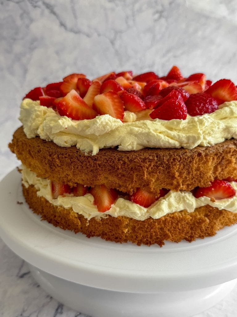 Strawberry cloud cake with mascarpone cream, served whole on a white cake stand.