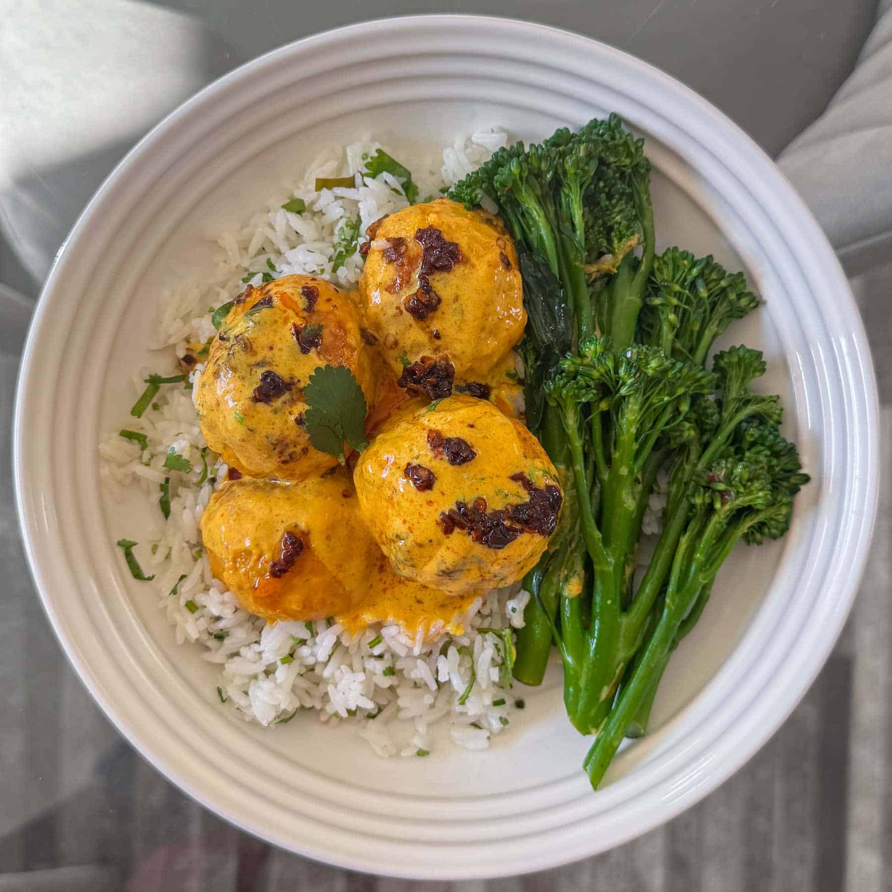 Thai curry chicken meatballs, served in a white bowl with rice and vegetables