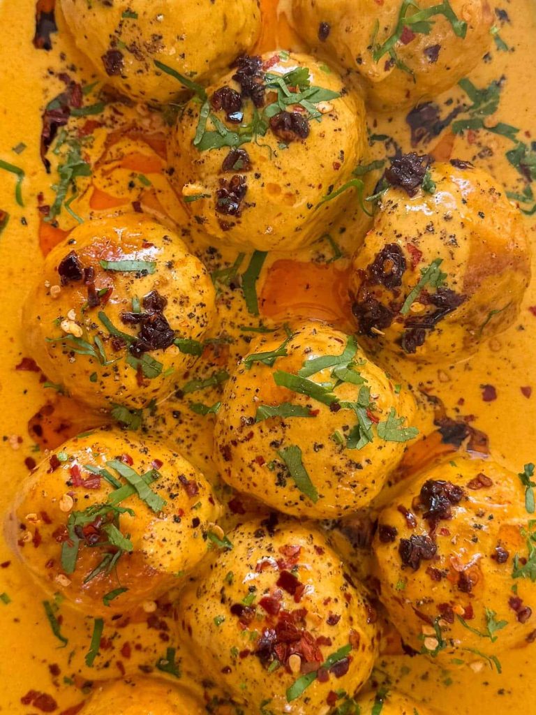 A closeup of Thai curry chicken meatballs served on a white shallow bowl