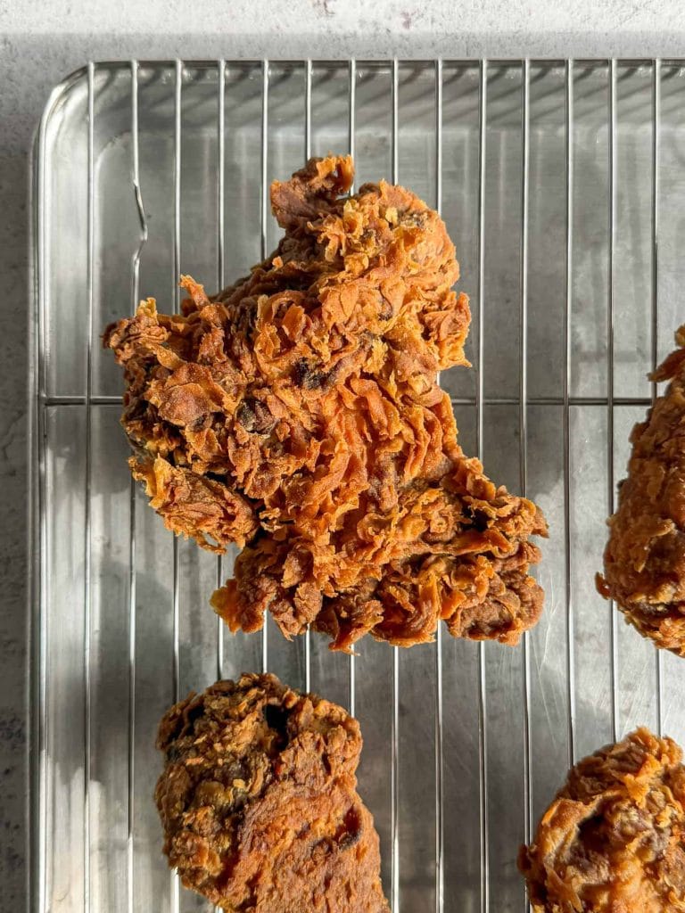 A close up of tom yum fried chicken, resting on a wire rack