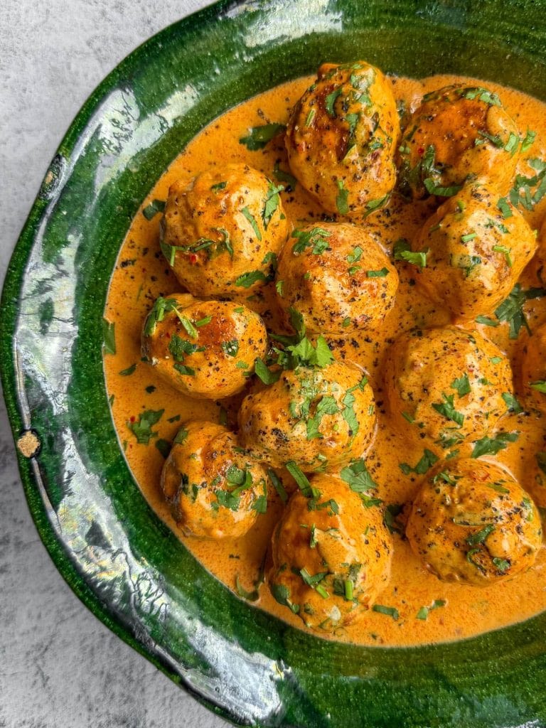 Coconut harissa chicken meatballs, served in a green platter.