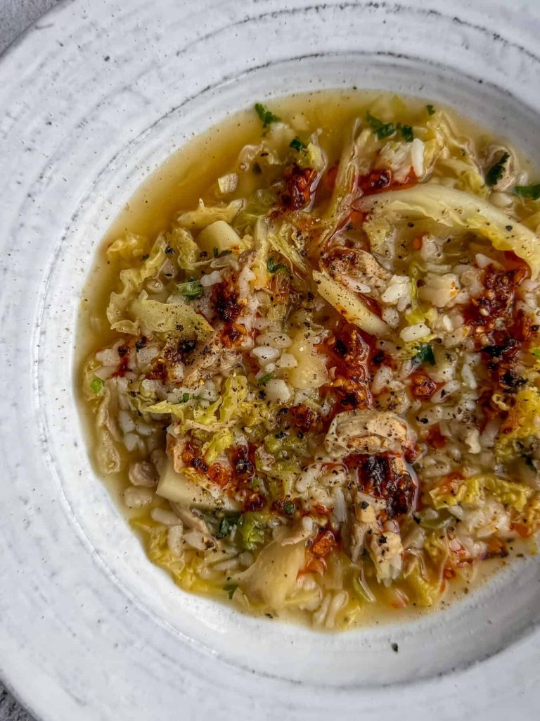 A serving of ginger and lemongrass chicken cabbage soup, topped with chilli oil.