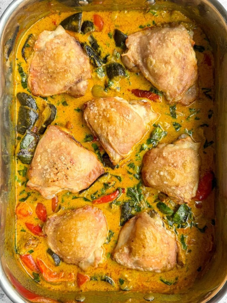 Thai curry chicken traybake with golden chicken thighs, roasted vegetables and Thai red coconut curry sauce