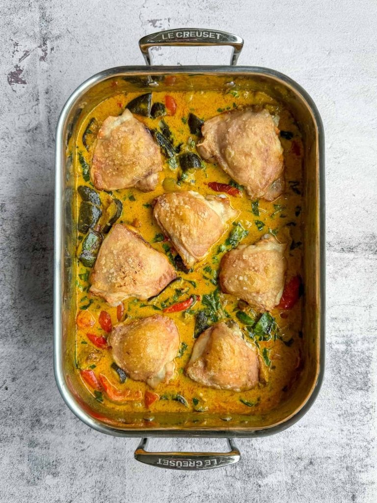 Thai curry chicken traybake with golden chicken thighs, roasted vegetables and Thai red curry sauce