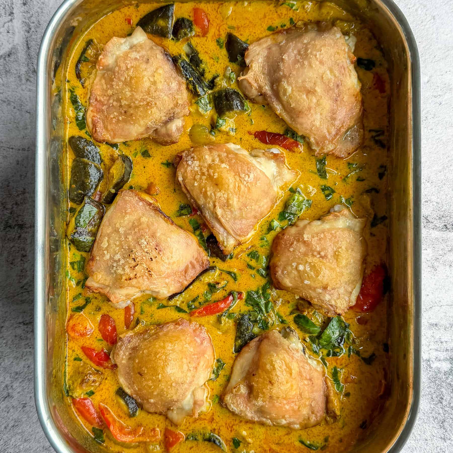 Thai curry chicken traybake with golden chicken thighs, roasted vegetables and coconut curry sauce